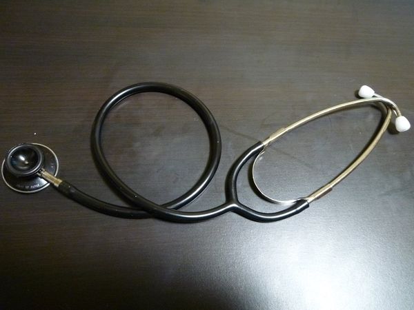 A stethoscope lying on a dark wooden table