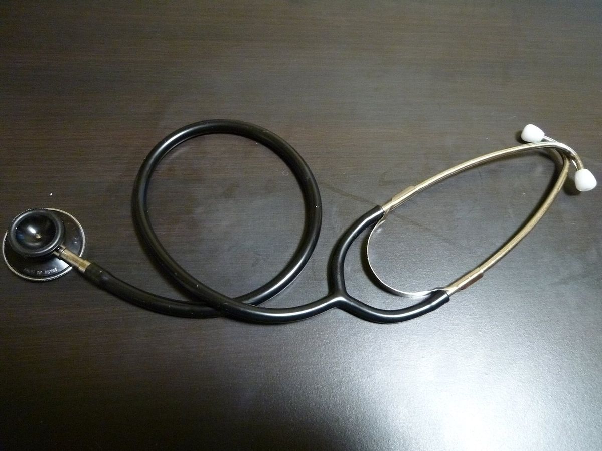 A stethoscope lying on a dark wooden table