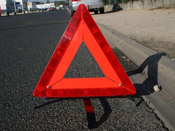 A red reflective warning triangle set on the pavement at the edge of a road
